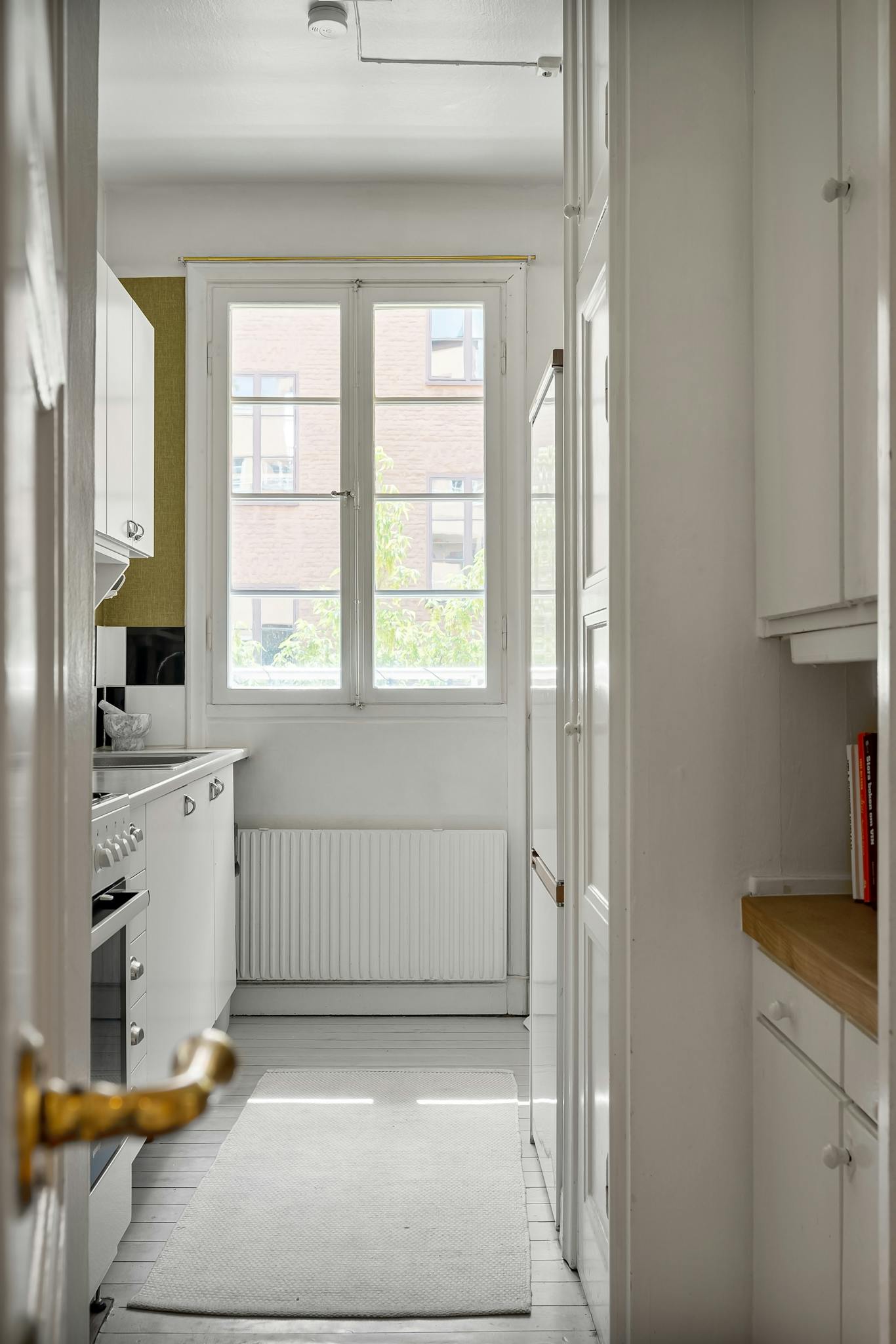 a modern white kitchen featuring large windows