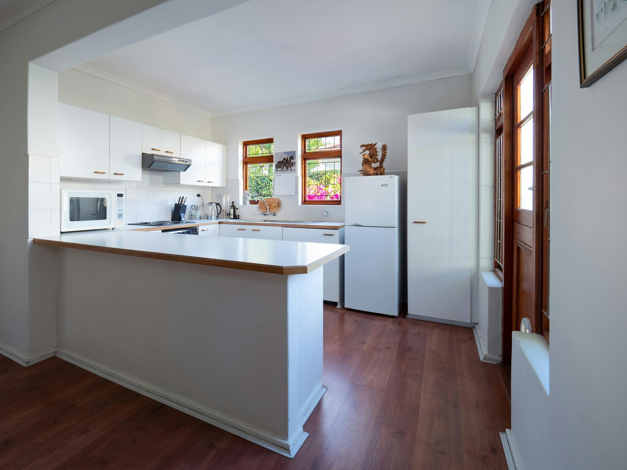 bright kitchen with white cabinets appliances and